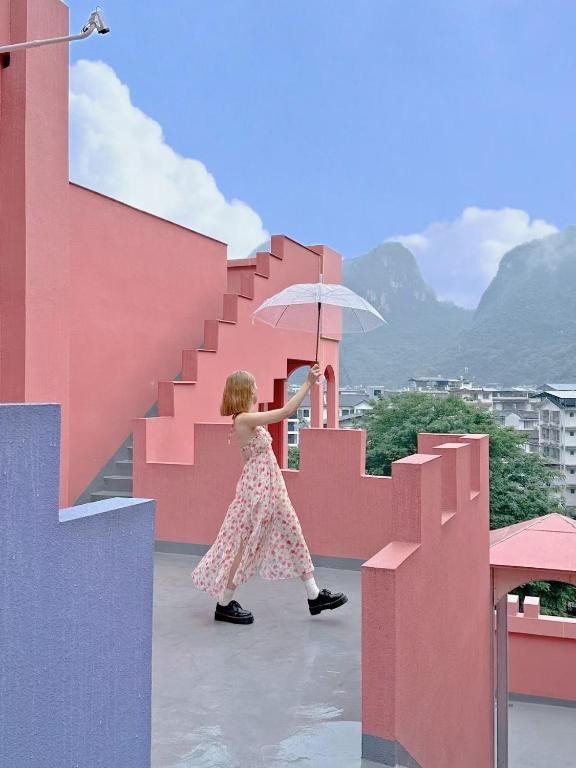 a girl walking up the stairs with an umbrella at Yangshuo B&G Hotel-Exclusive location,Roof Top Viewing Terrace,Seasonal swimming pool,Free Self-Service Laundry & Drying, Entrance Ticket Serivce, Local Trip plan,E-Scooter& English Customer Service in Yangshuo