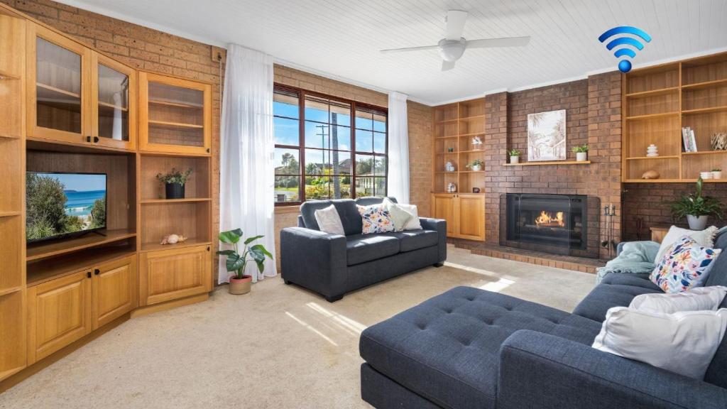 a living room with two couches and a fireplace at The Callala Hideaway in Callala Beach