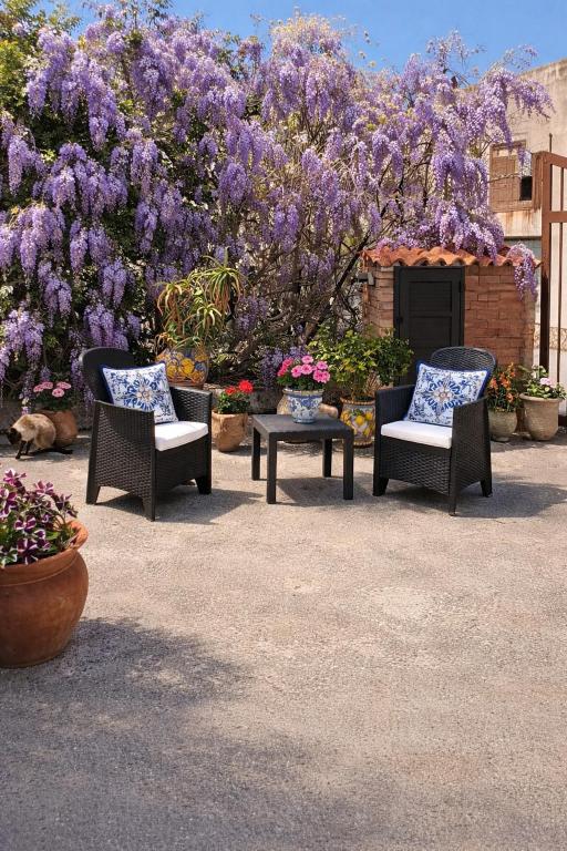 three chairs and a table in front of a tree with purple flowers at Stella Marina Sea & Sun in Cefalù