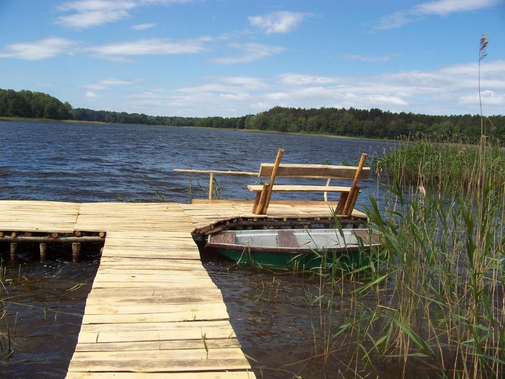 a wooden dock with a chair sitting on top of a lake at Biały Domek in Radęcin