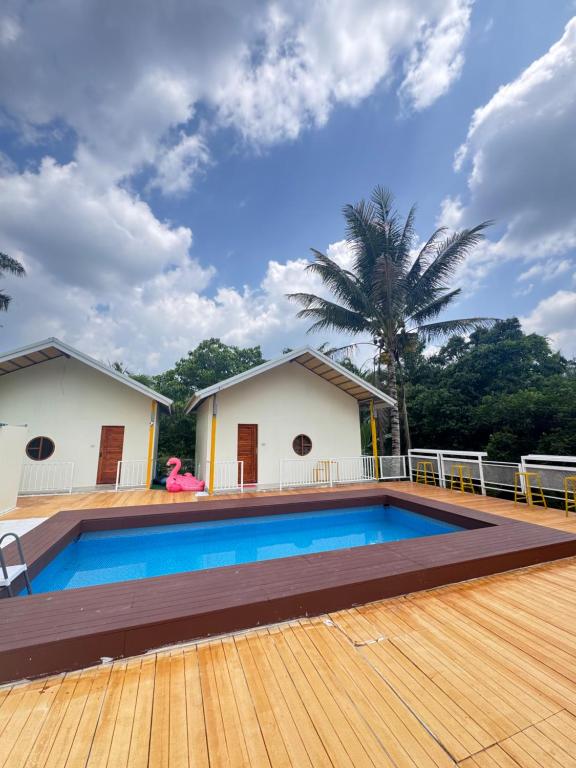a swimming pool with a wooden deck and a house at Khaosok Embrace Resort in Khao Sok National Park
