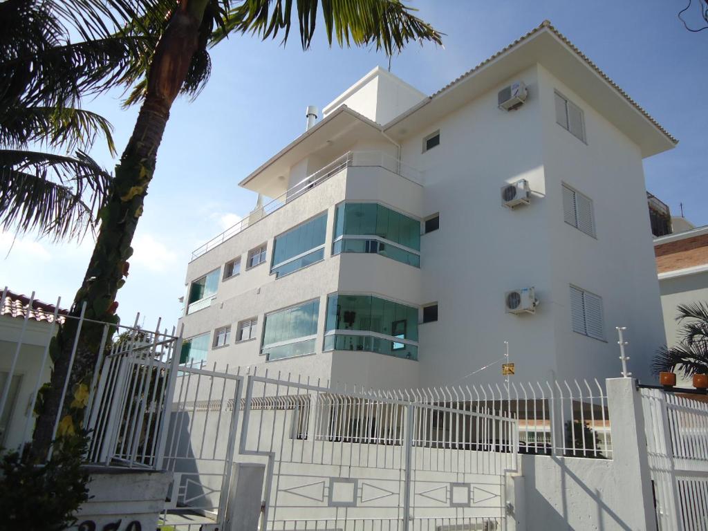 un edificio blanco con una valla delante en Lindo apartamento, com excelente localização, em Jurerê!, en Florianópolis