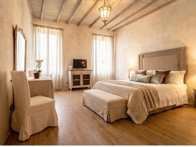 a bedroom with a large bed and a chair at Corte del Cedro in Provaglio d'Iseo