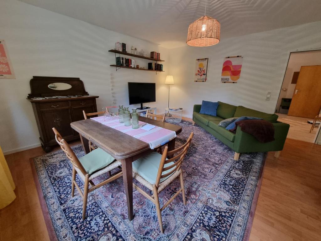 a living room with a table and a green couch at Gemütliche Ferienwohnung mit Blick ins Grüne in Wadern