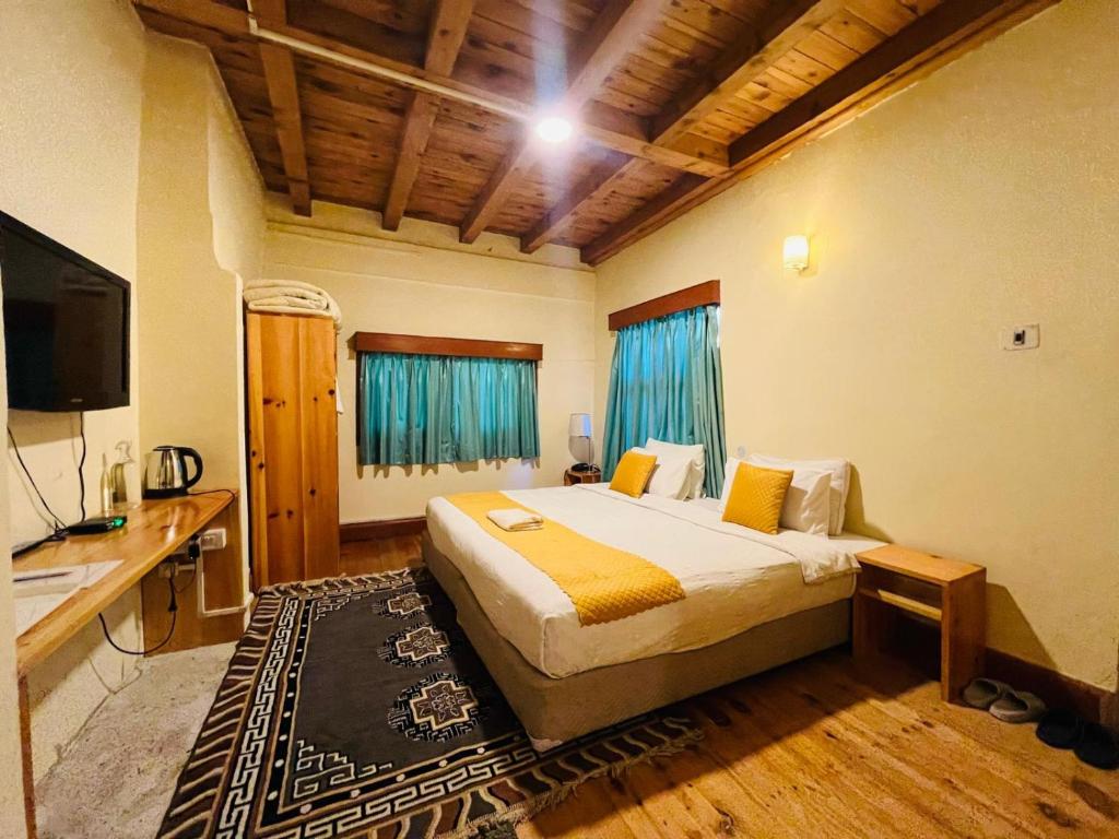 a bedroom with a bed and a desk and a television at sinchula Villa Resort in Paro