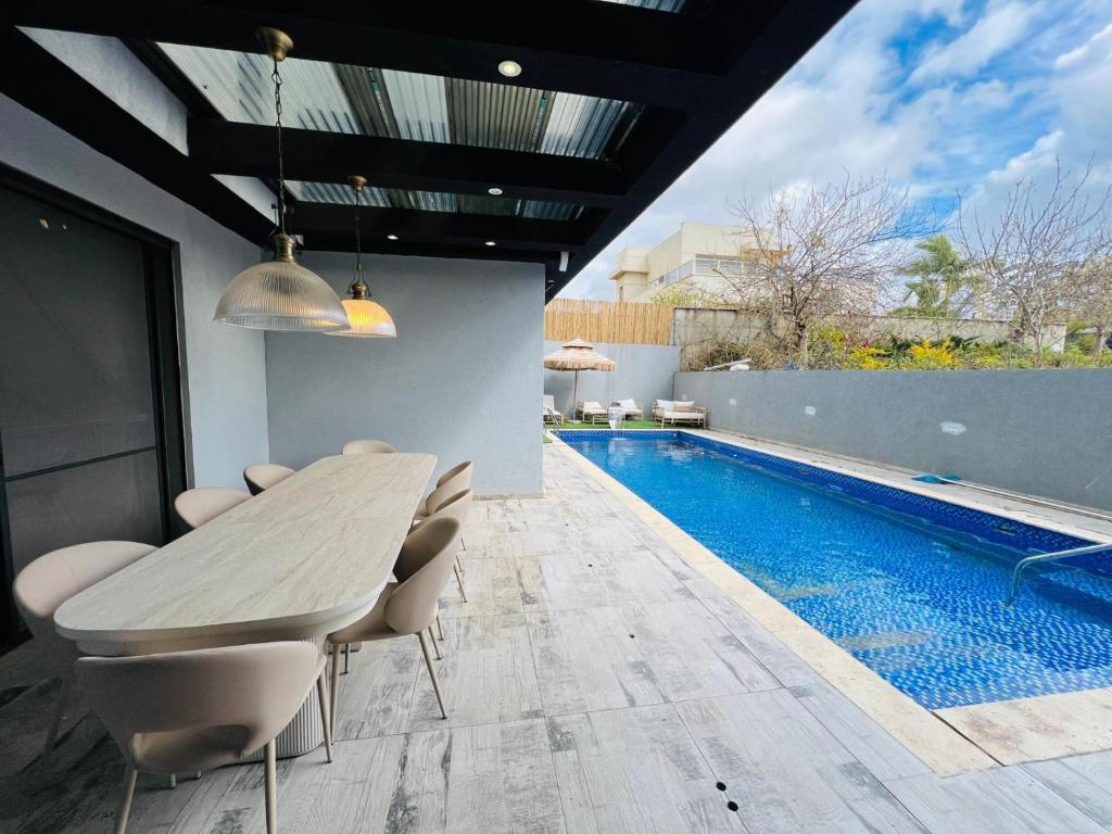 a dining table and chairs next to a swimming pool at Villa Sol Aviv - וילה מושלמת עם בריכה פרטית למשפחות וקבוצות בנתיבות in Netivot