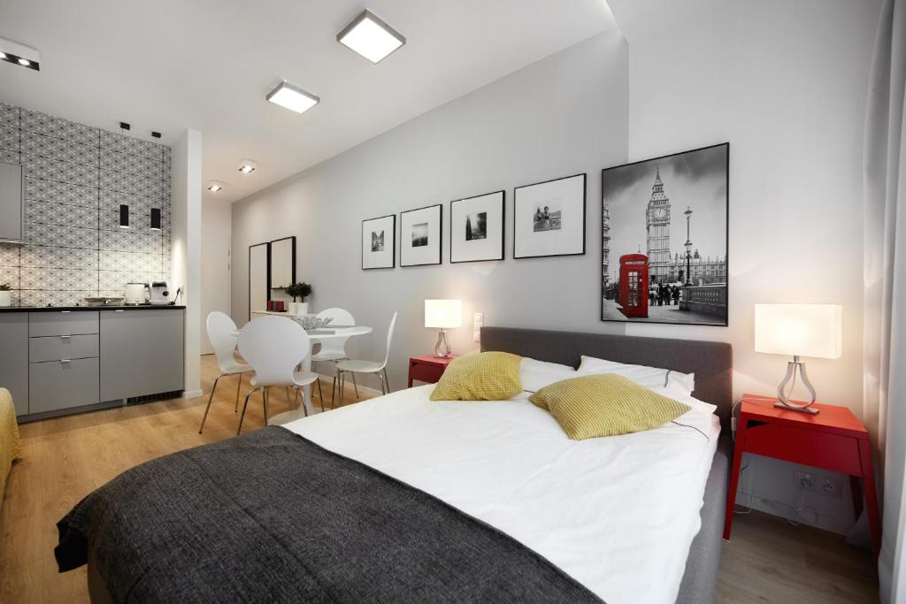 a bedroom with a large white bed and a kitchen at Kalia Apartments in Warsaw