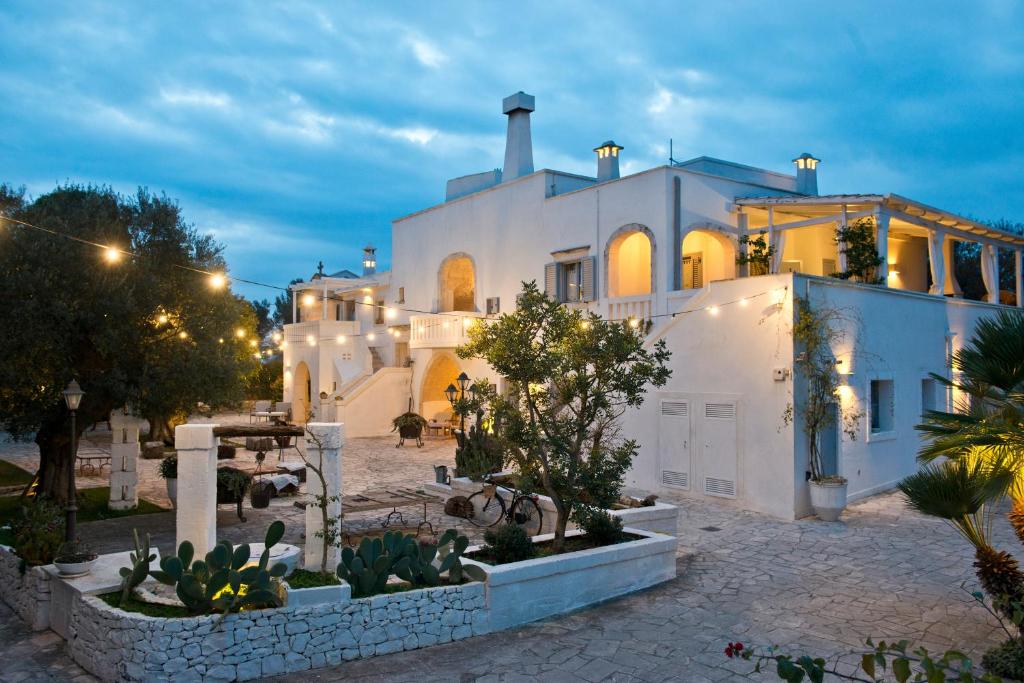 une grande maison blanche avec beaucoup de plantes dans l'établissement Masseria Salinola, à Ostuni