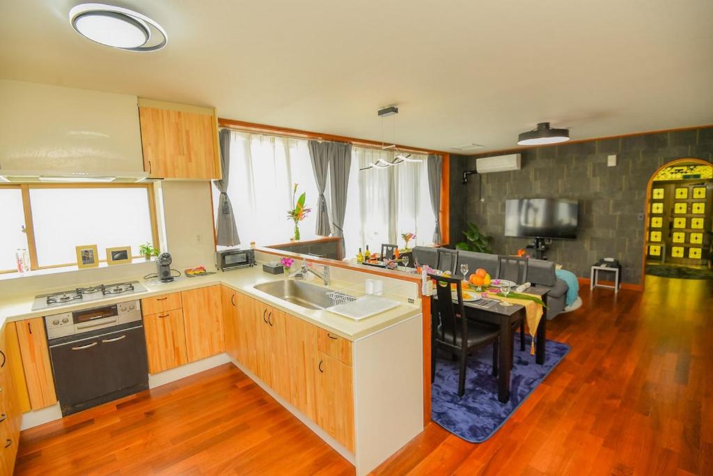a kitchen with wooden cabinets and a table and a dining room at TIDA house urasoe in Urazoe