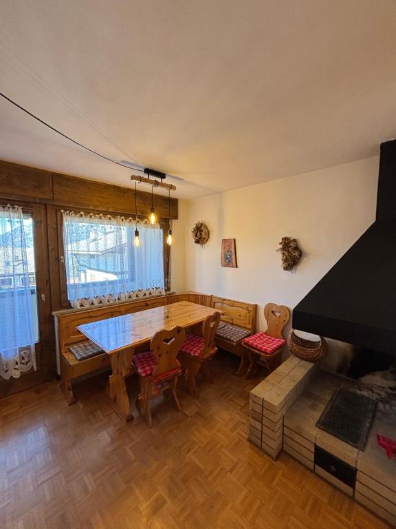 a living room with a table and chairs and a piano at Pragma Apartments - Cupido's Alpine Nest in Bellamonte