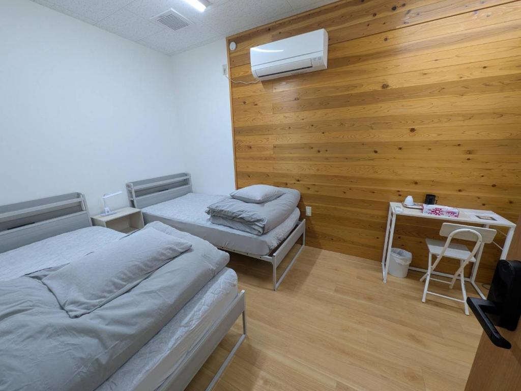 a bedroom with two beds and a desk with a chair at hostel 丹鶴 in Shingū