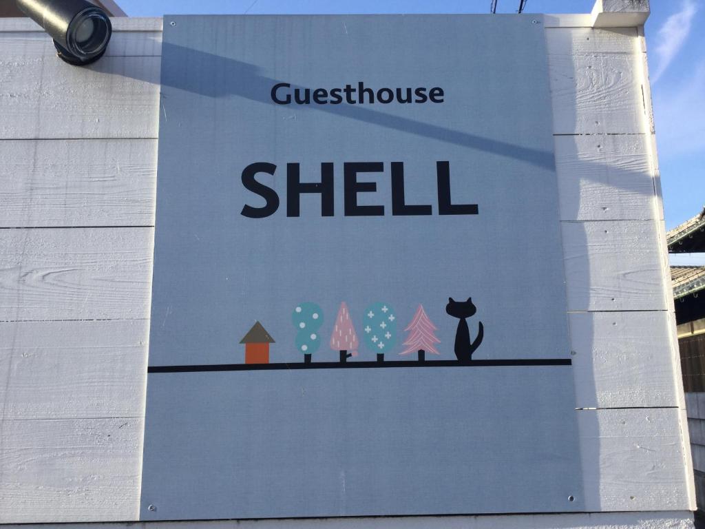 un panneau sur le côté d'un bâtiment dans l'établissement Guesthouse SHELL, à Naoshima