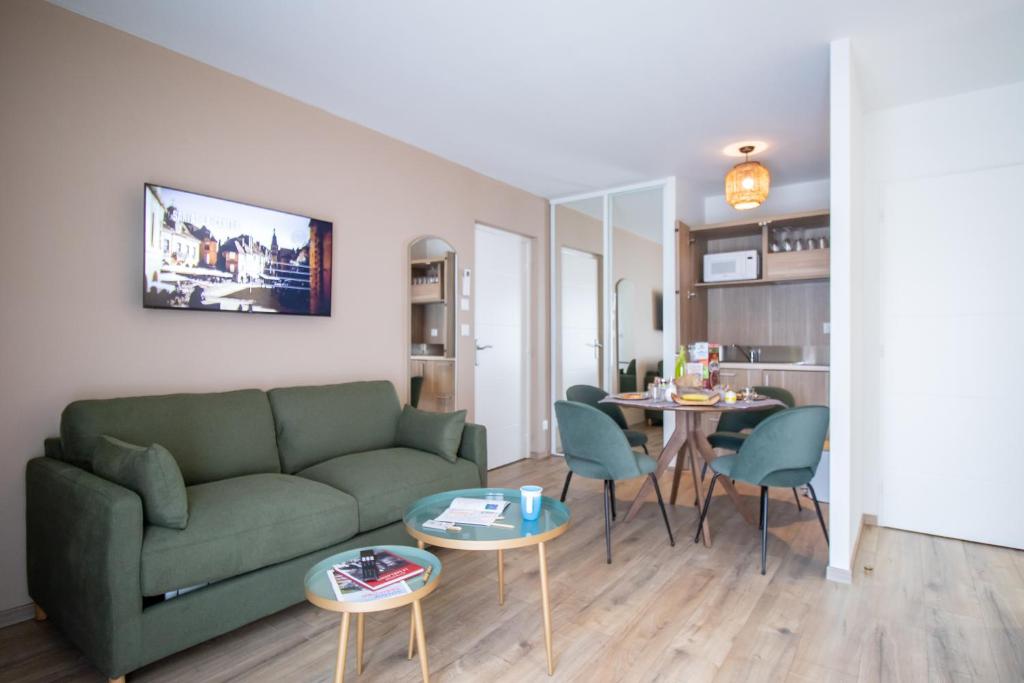 a living room with a green couch and a table at Hotel Le Mas de Castel - Piscine chauffee in Sarlat-la-Canéda