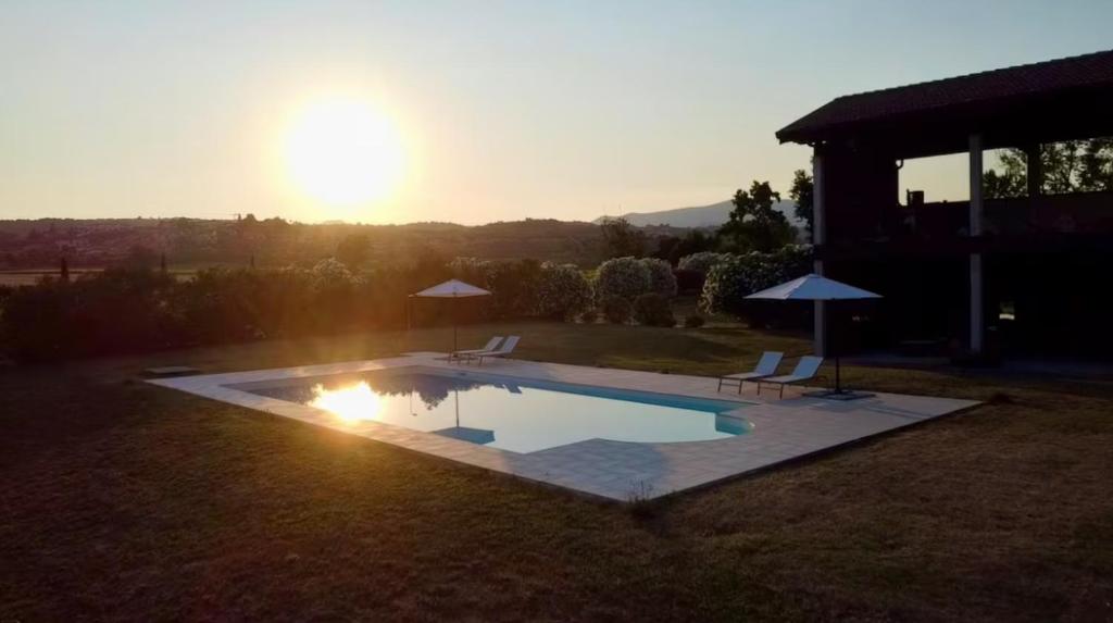 a swimming pool in a yard with the sun setting at Tenuta La Macina in Polpenazze del Garda