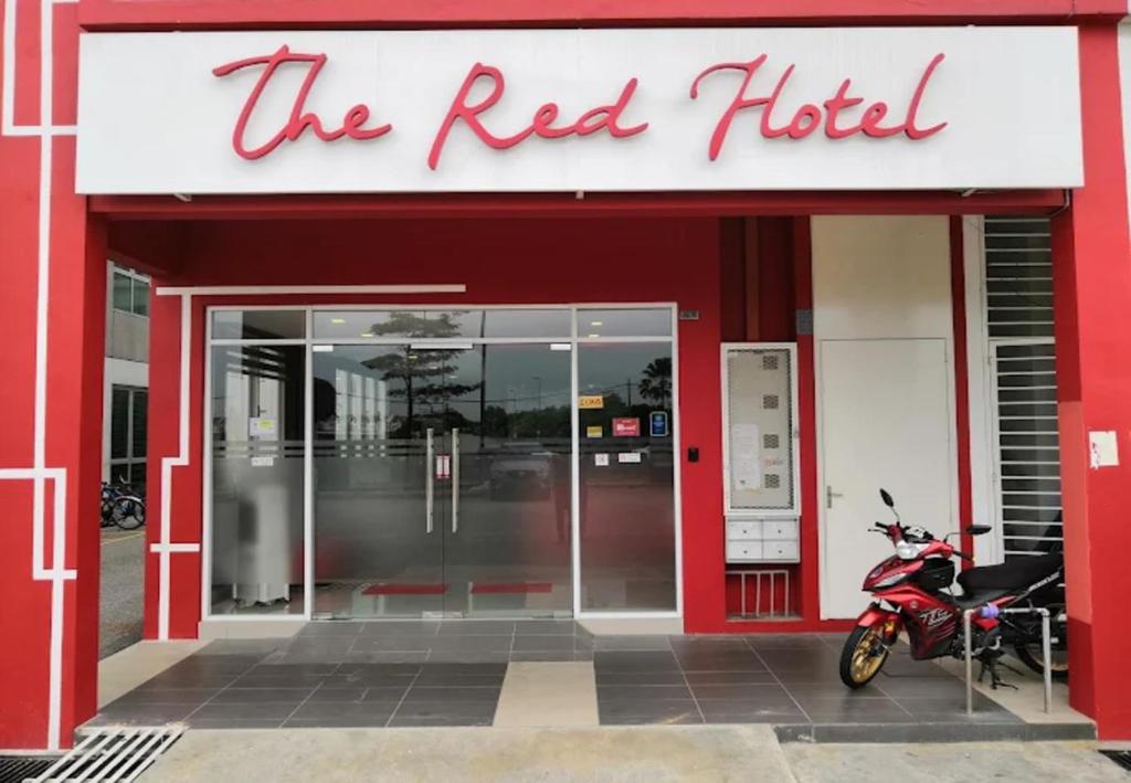 a motorcycle parked in front of a red building at The Red Hotel in Bandar Saujana Putra
