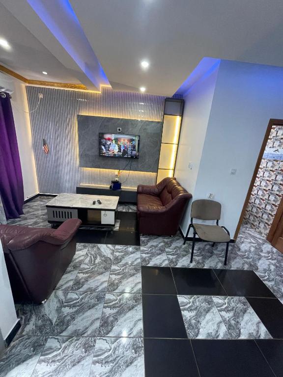 a living room with couches and a tv at MB California Guest House in Bonabéri