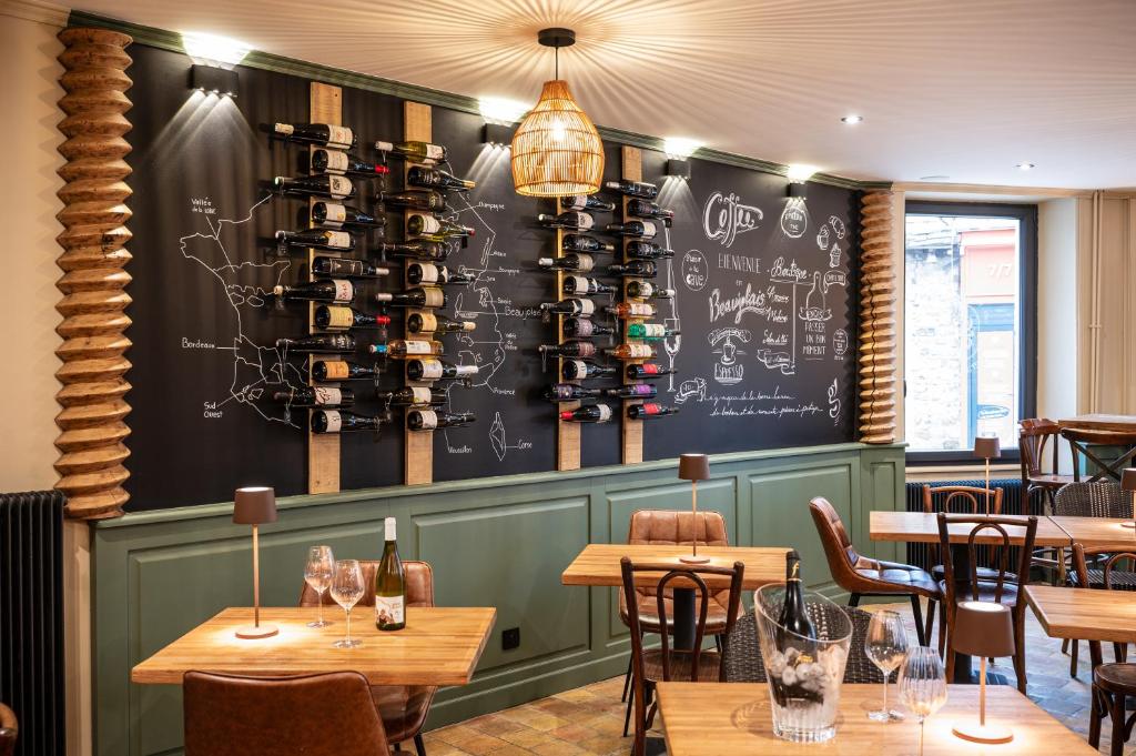 a restaurant with tables and a chalkboard wall with wine bottles at Un grain d'folie in Villié-Morgon