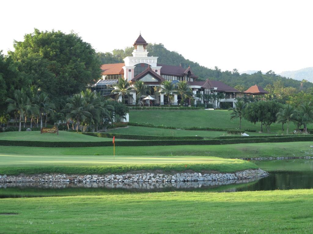a golf course with a resort in the background at Springfield Village Golf & Spa in Cha Am