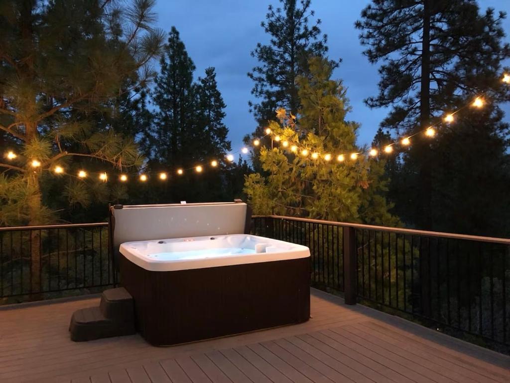 a bath tub sitting on a deck with lights at Large Deck & Spa & Games & Vaulted Ceiling Cabin in Groveland