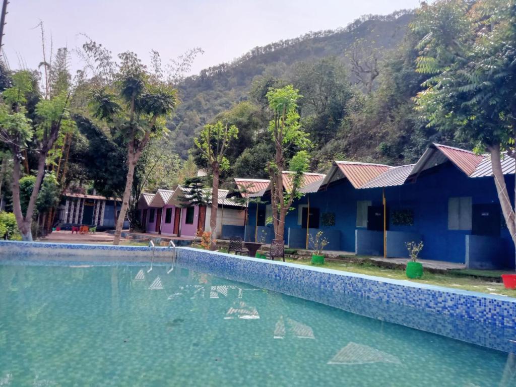 a resort with a swimming pool in front of a mountain at Hills Queen Resort And Camping in Mohan Chatti