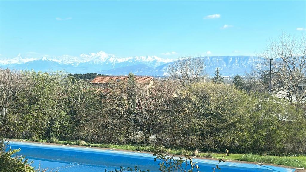 a swimming pool with trees and mountains in the background at Charmante chambre Chalet in Crozet