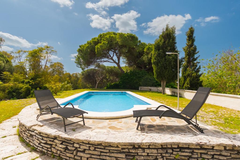 two chairs and a swimming pool in a yard at Panther Home El Ancla Villa Premium con Piscina Privada in El Puerto de Santa María