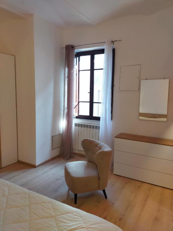 a bedroom with a chair and a window at La Finestra sul Corso 3 in Arcidosso