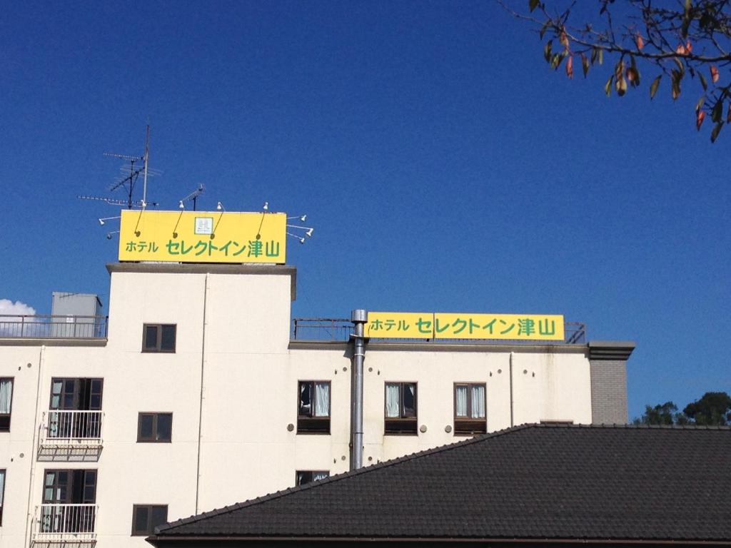 a building with a yellow sign on top of it at Hotel Select Inn Tsuyama in Tuyama