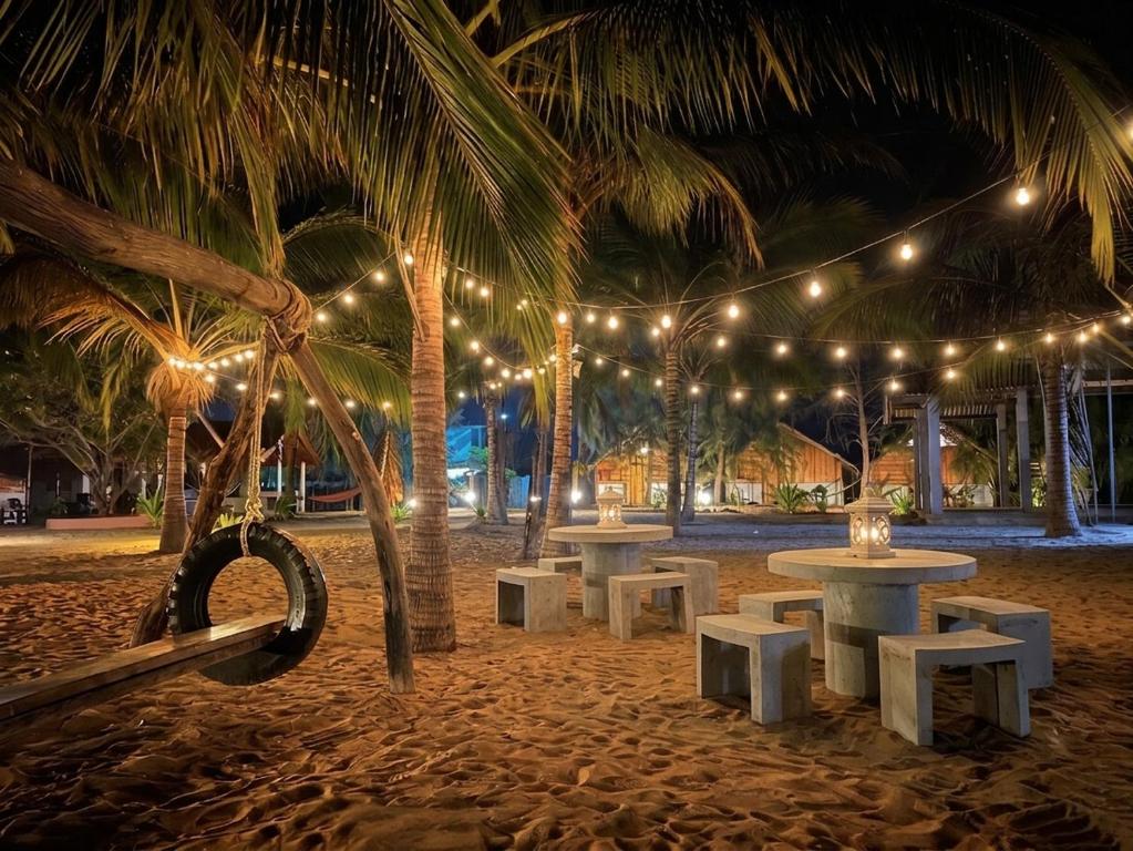 a row of tables and chairs on a beach with lights at Sand Dune Beach Hotel & Surf Camp in Arugam Bay