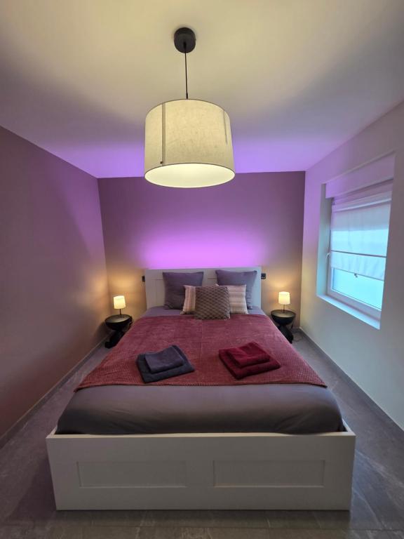 a purple bedroom with a bed with two towels on it at Flexi flat Gosselies Providence 11 in Charleroi