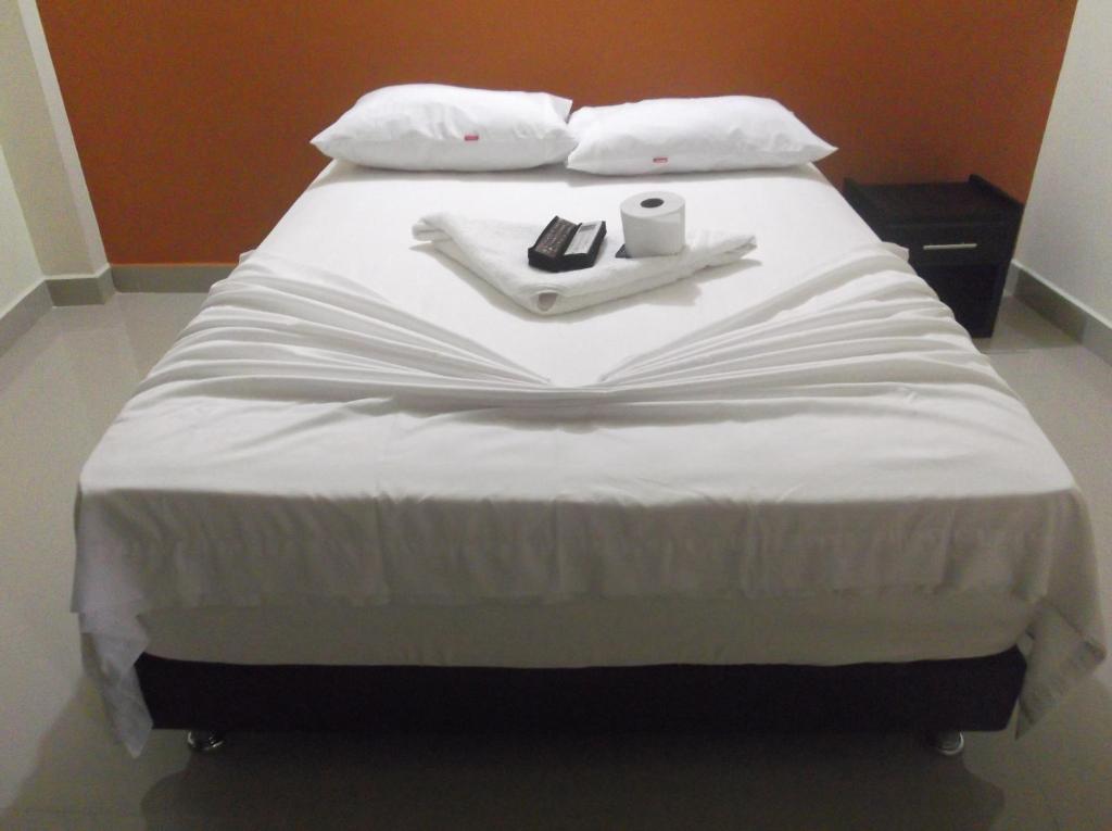 a white bed with a book and a candle on it at Hotel Monarca Putumayo in Orito