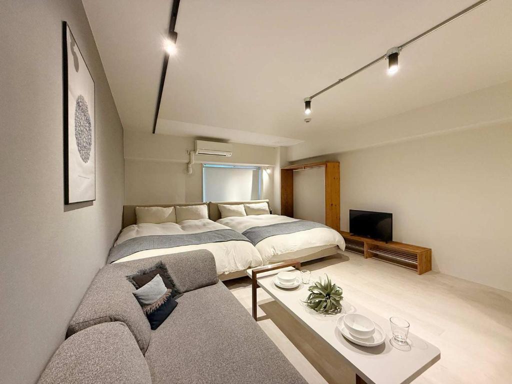 a bedroom with a large bed and a couch at Origaminn 702 by b hotel - 5 mins PeacePark in Hiroshima