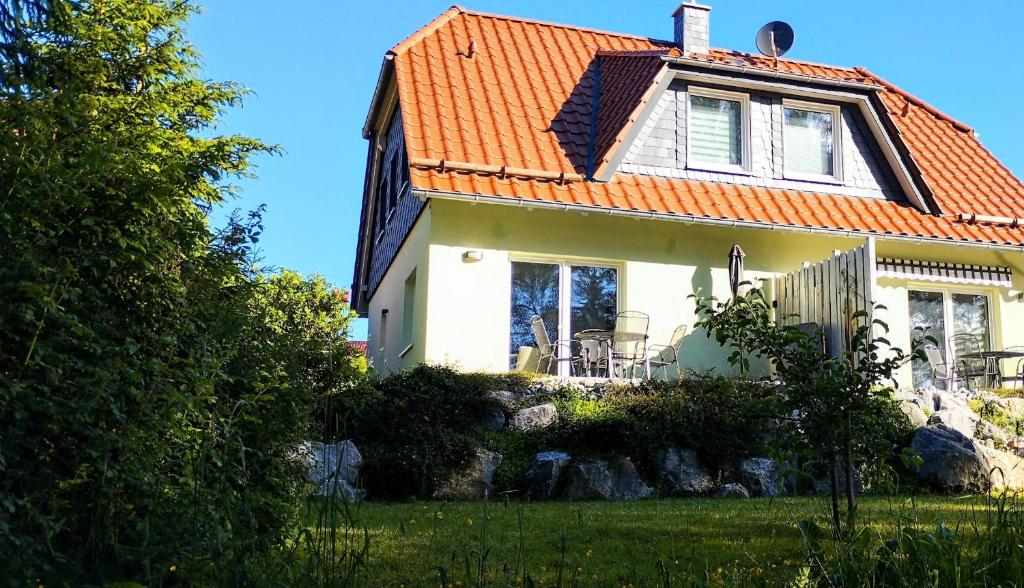 a white house with an orange roof at Behagliches Ferienhaus Zaunkönig -mit Kamin und Sauna- Blick über das romantische Bodetal in Tanne
