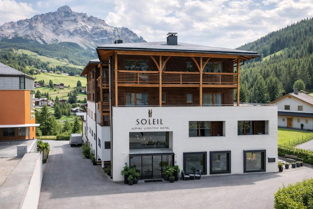 a large white building with a mountain in the background at Soleil Alpine Lifestyle Hotel in La Villa