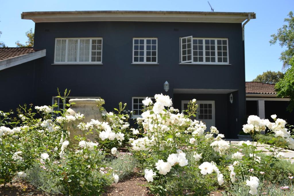 una casa negra con flores blancas delante en The Garden Shed Guest House, en Wellington