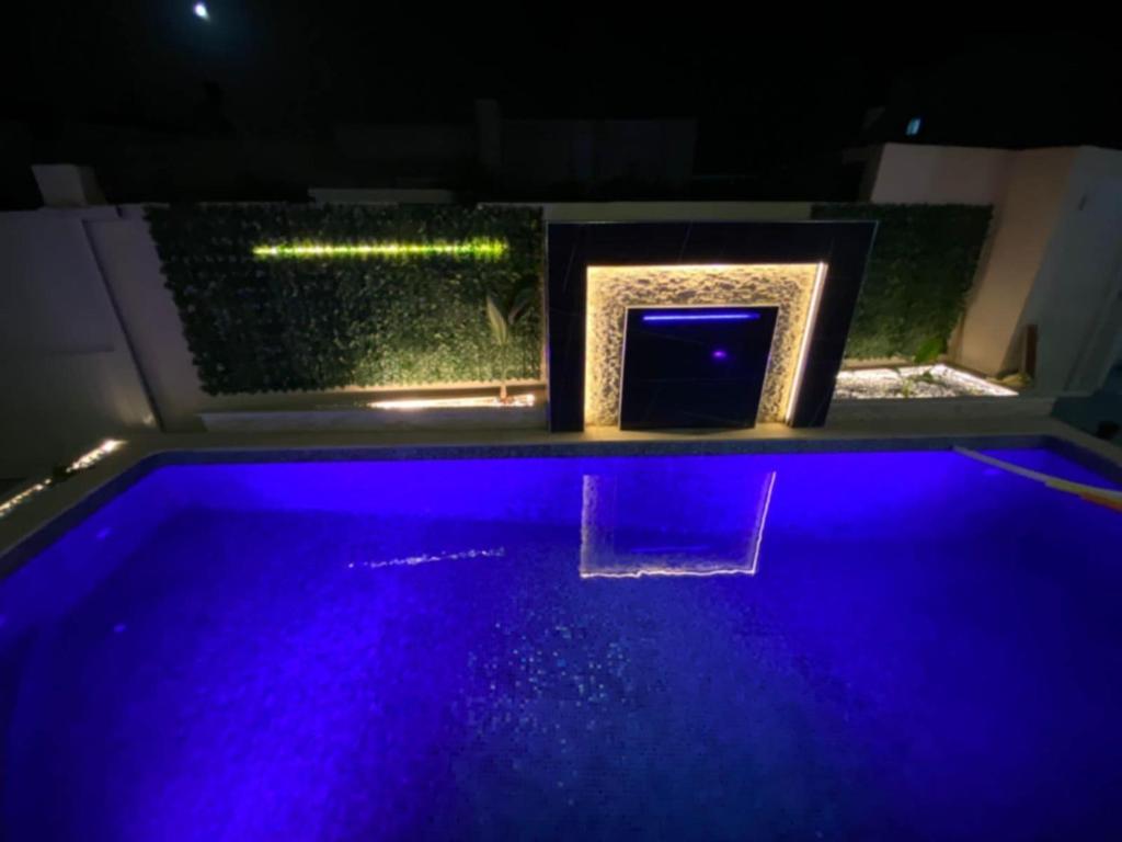 a swimming pool with blue lights in a room at Villa RAZAN in Midoun