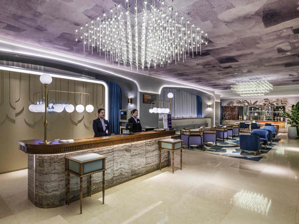 a rendering of a hotel lobby with two men standing at a bar at Mercure Shanghai Global Harbour in Shanghai