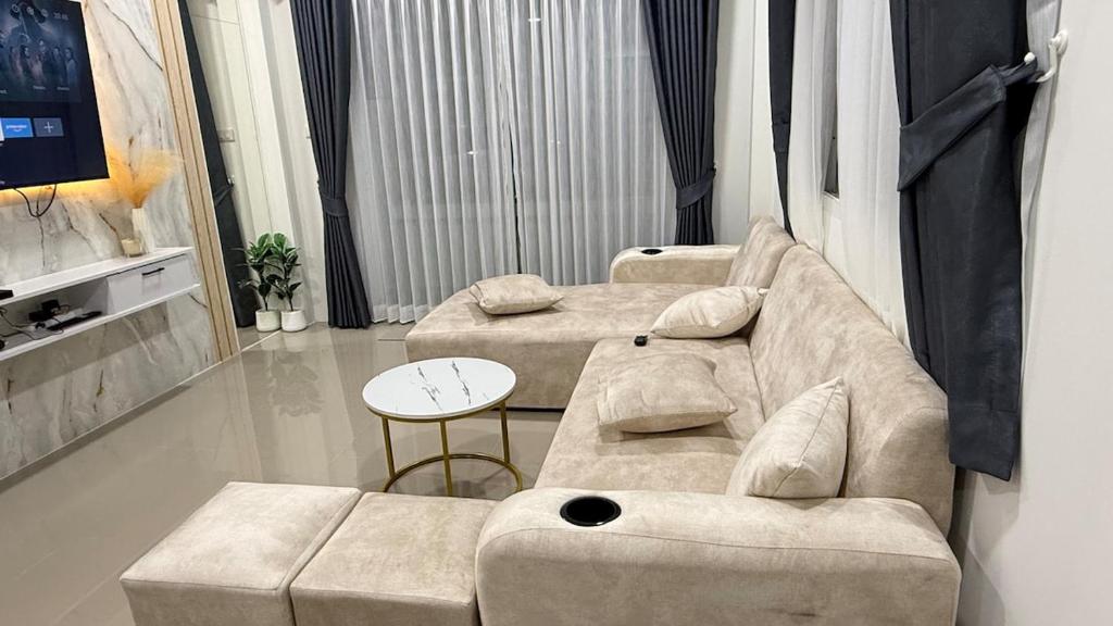 a living room with two couches and a table at Baan Thanaluk 1 Pattaya in Pattaya