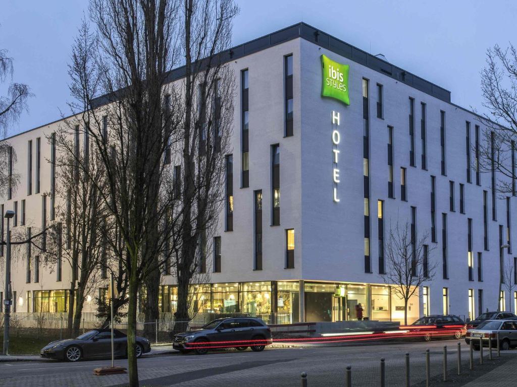 a large white building with a green sign on it at ibis Styles Stuttgart Vaihingen in Stuttgart
