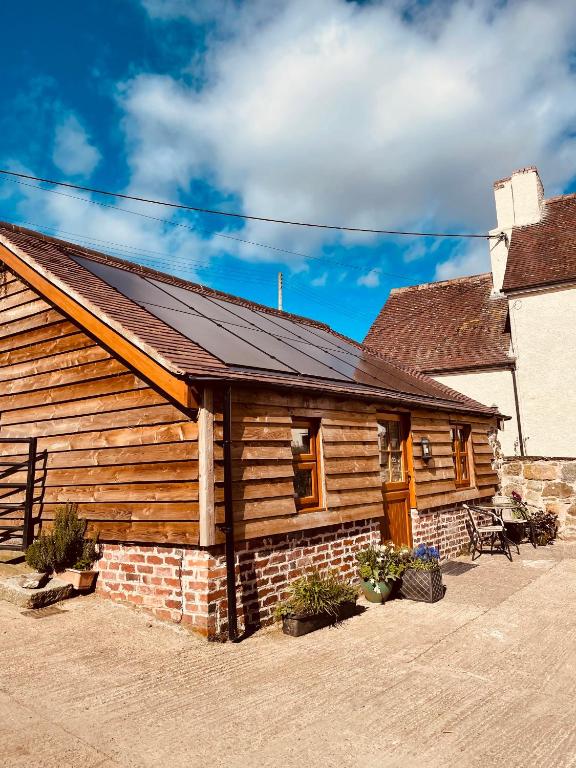 a log cabin with a solar roof on it at Enchmarsh Farm Byre in Church Stretton