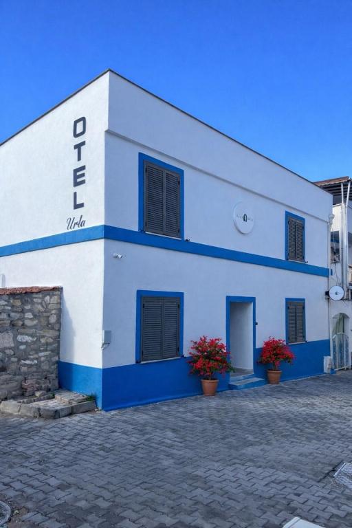 ein weiß-blaues Gebäude mit roten Blumen davor in der Unterkunft KE Urla in Urla