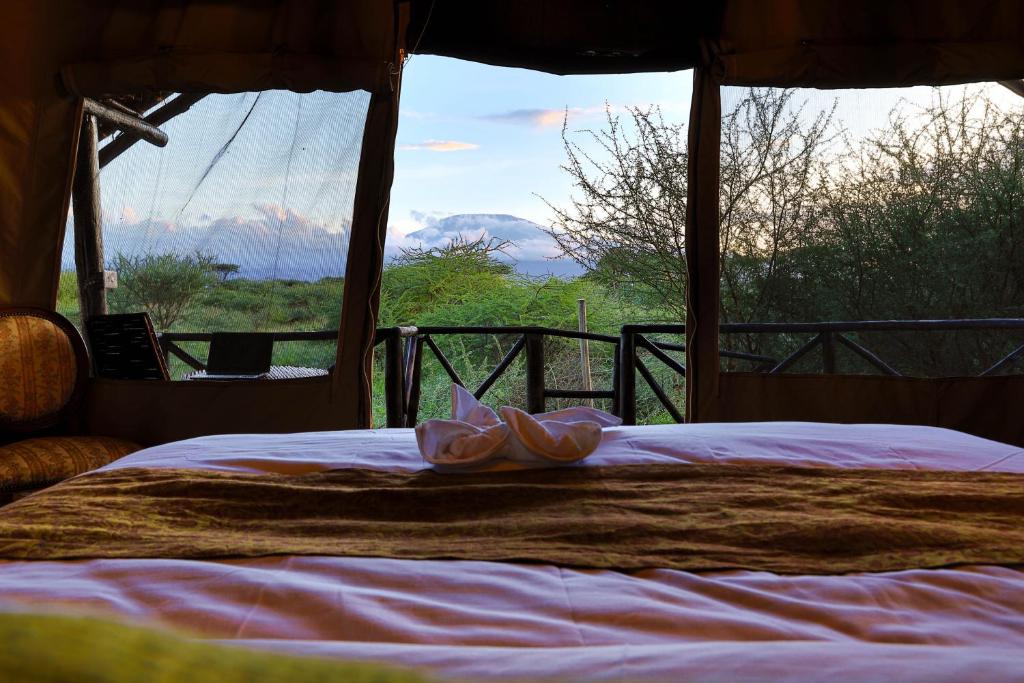 a bed with flowers on it in front of a window at Olemayian Amboseli Cottages in Amboseli