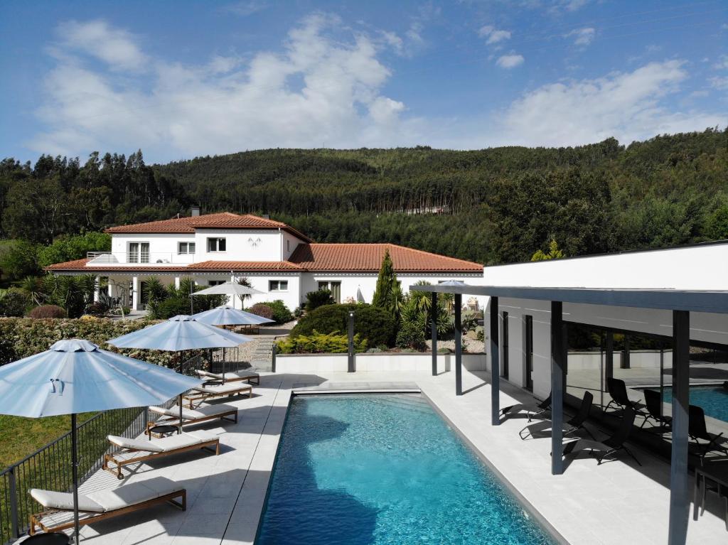 a swimming pool with chairs and umbrellas next to a house at Casa Carvalhal - Adults Only in Góis