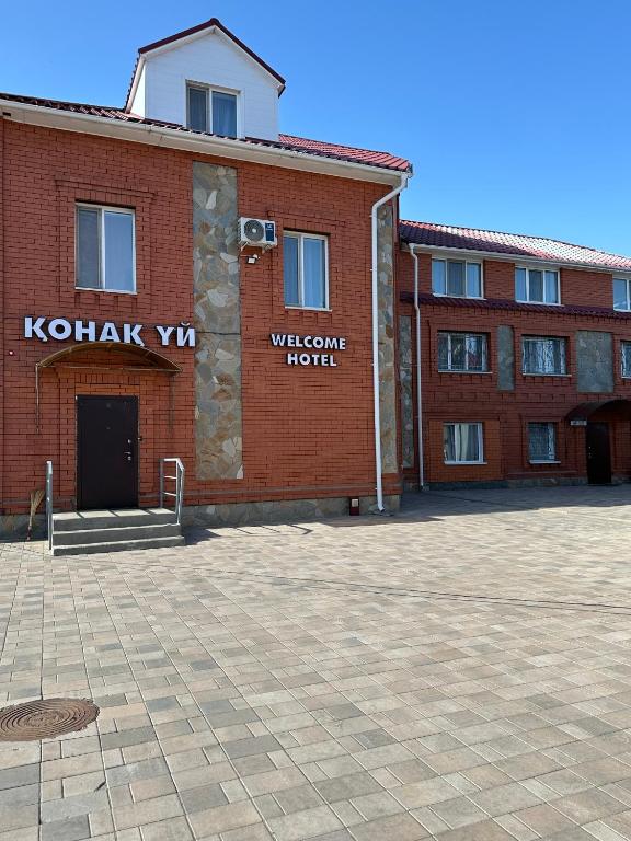 a red brick building with a welcome hotel sign on it at Welcome Hotel in Kostanay