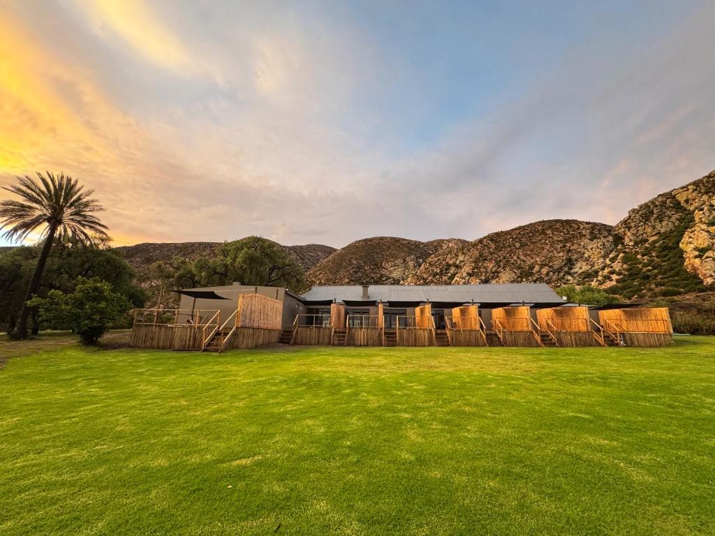 a house in a field with mountains in the background at Toorwater Spa in Uniondale