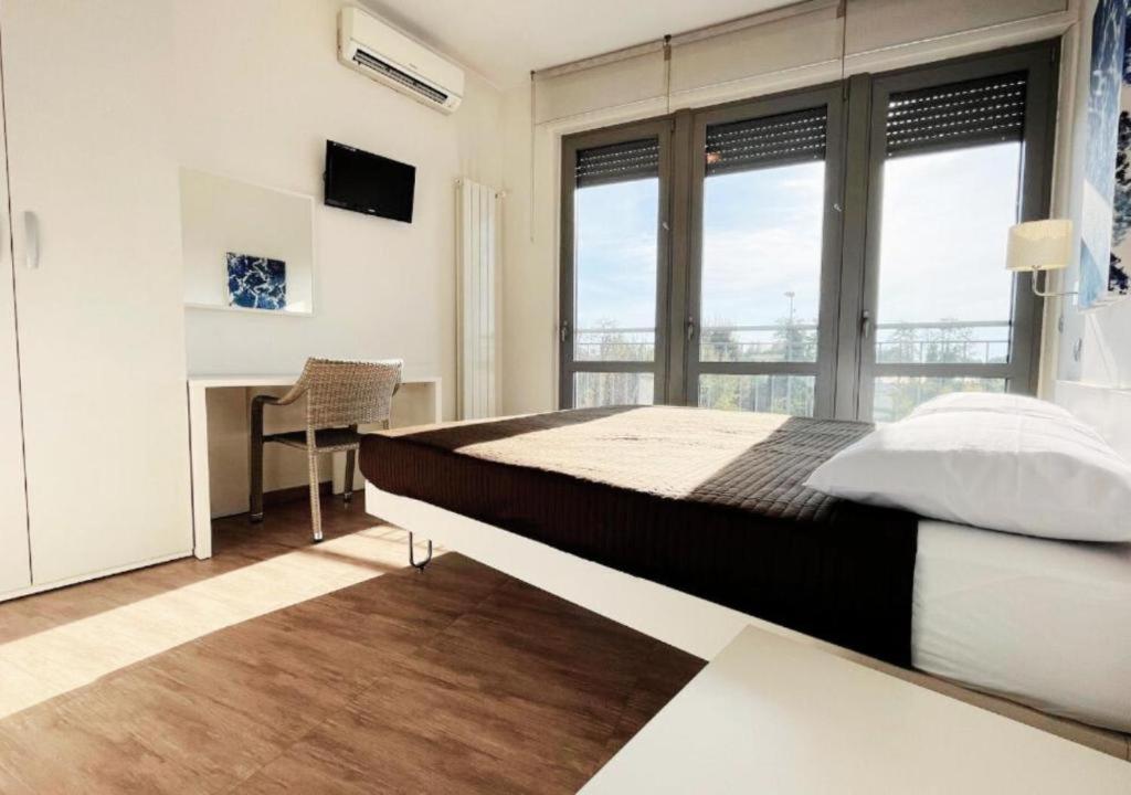 a bedroom with a bed and a desk and windows at Casa Makeda in Rosate