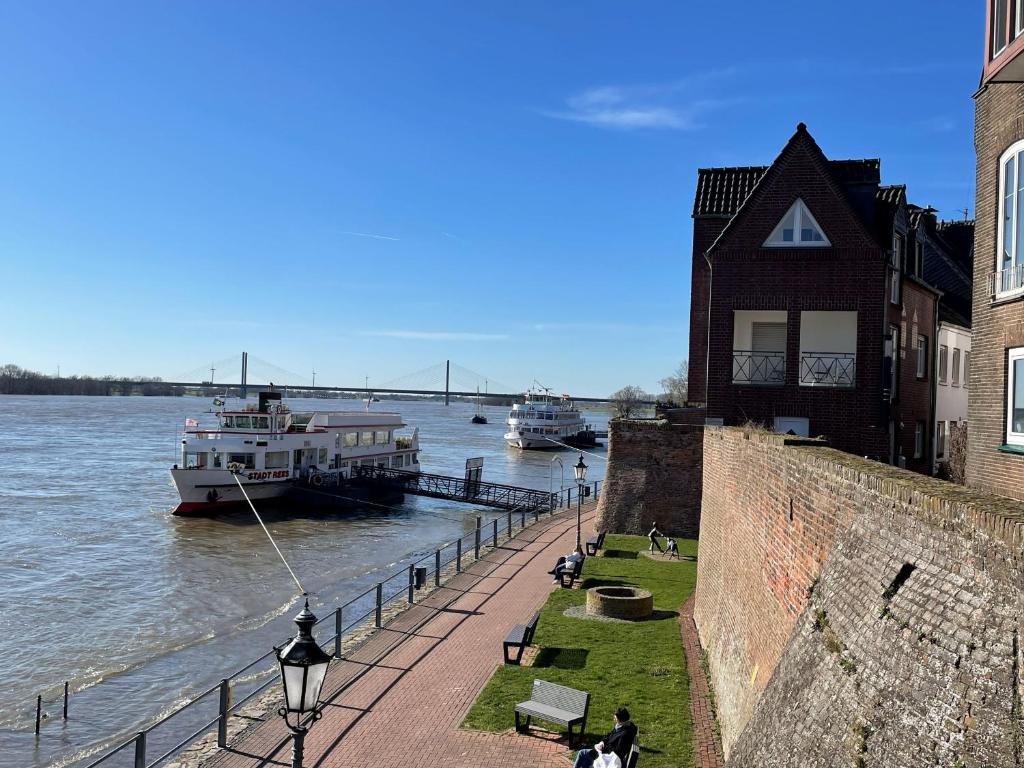 two boats are docked on the river next to a building at Haus Fährblick in Rees