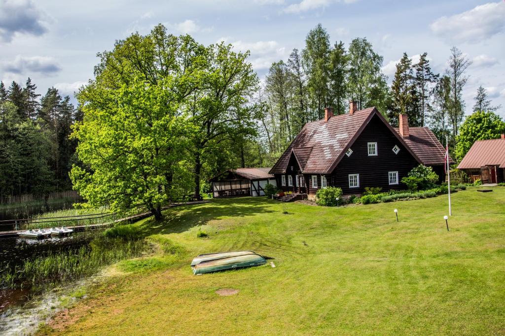 a large house on a field next to a river at Atpūtas un sporta komplekss Mednieki - atpūta dabā, pie ezera in Salainis