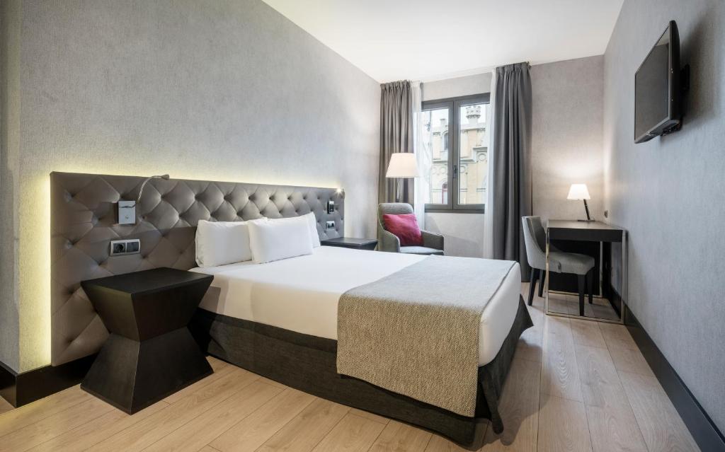 a hotel room with a large bed and a desk at Ilunion Bel-Art in Barcelona