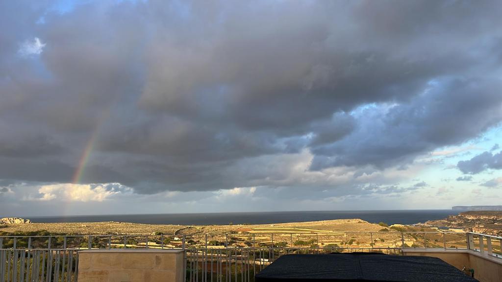 a rainbow in the sky over a city at Sunset Edge Villa - 77 Retreats in Għajn Tuffieħa